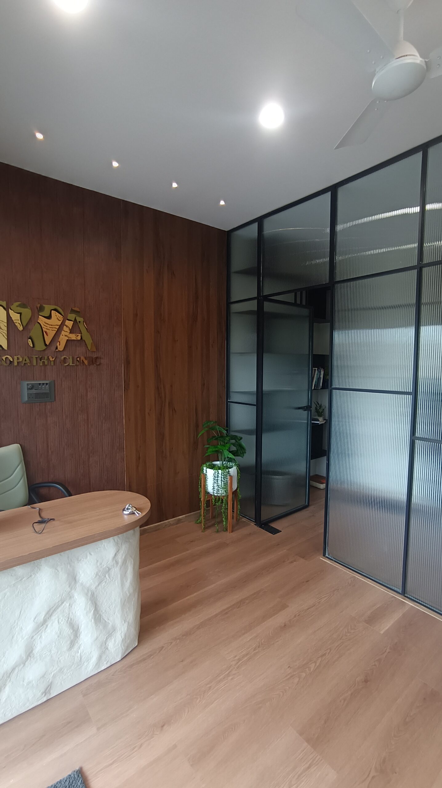 Bright reception or lounge area featuring a minimalist light‑wood desk, white reception counter, floor‑to‑ceiling glazing, light wood flooring.