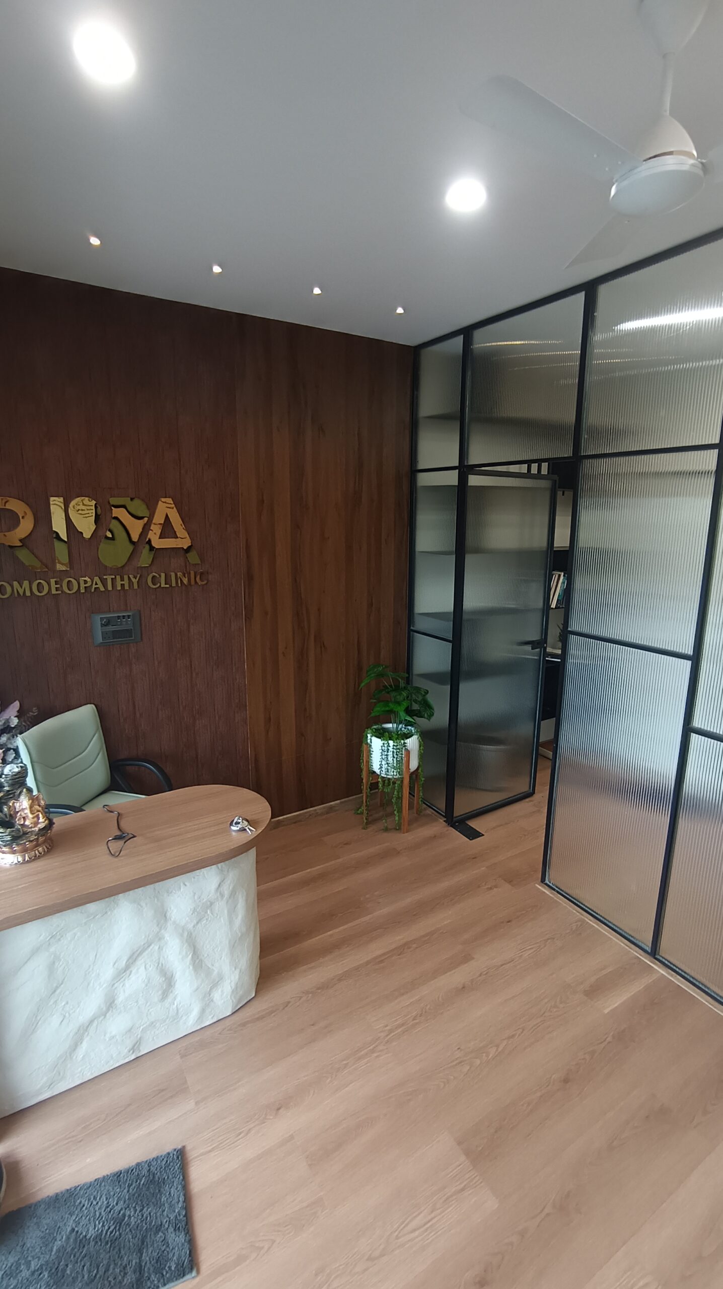 Modern office interior with a long central worktable, floating shelves mounted on a wood-paneled wall, and ergonomic chairs.