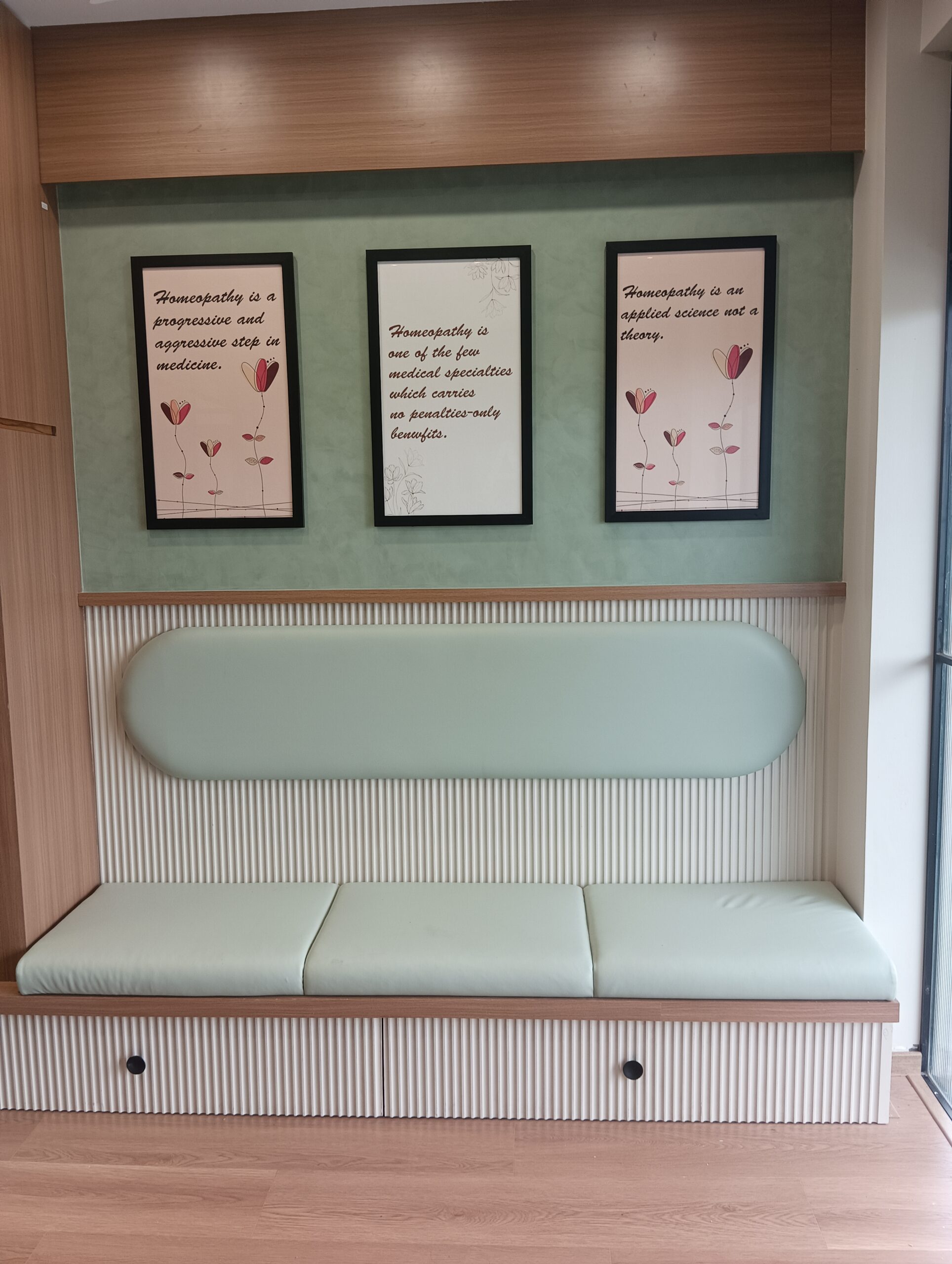Open‑plan office displaying a wooden workbench, green task chairs, bookshelves, and a neutral palette.