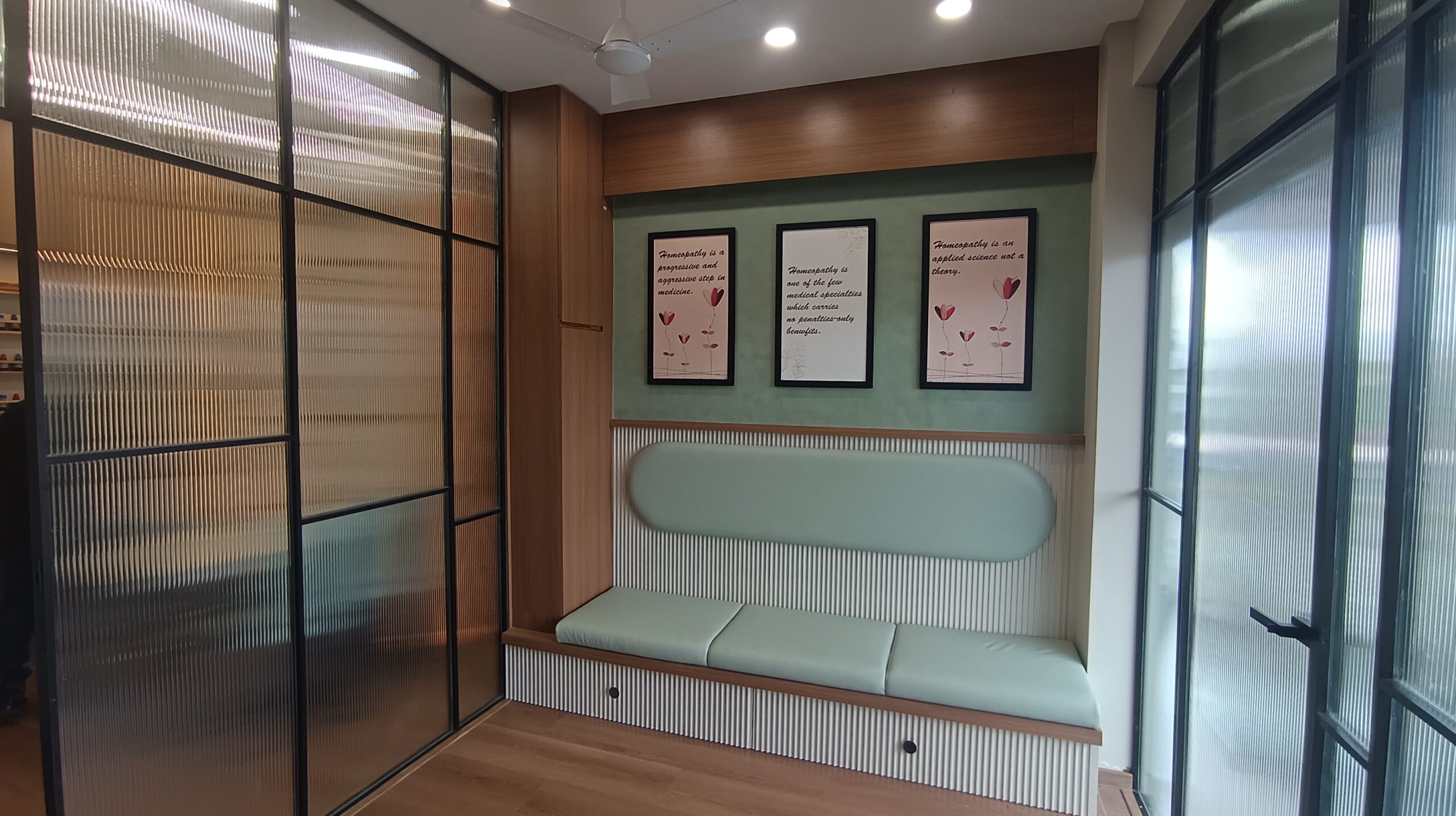 Reception area featuring a sleek countertop, built‑in signage display, light wood flooring, and floor‑to‑ceiling glazing.