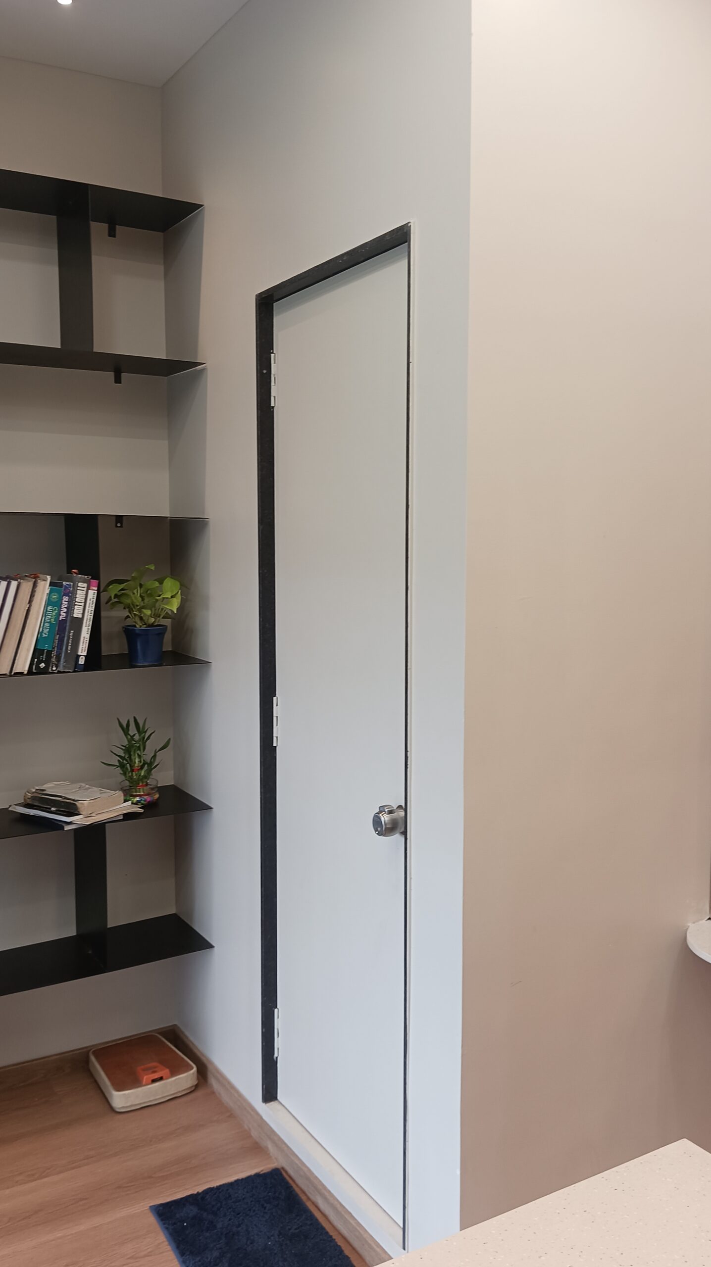 Open-plan office space featuring wooden desks arranged in rows, modern pendant lights hanging from the ceiling, and large windows bringing in natural light