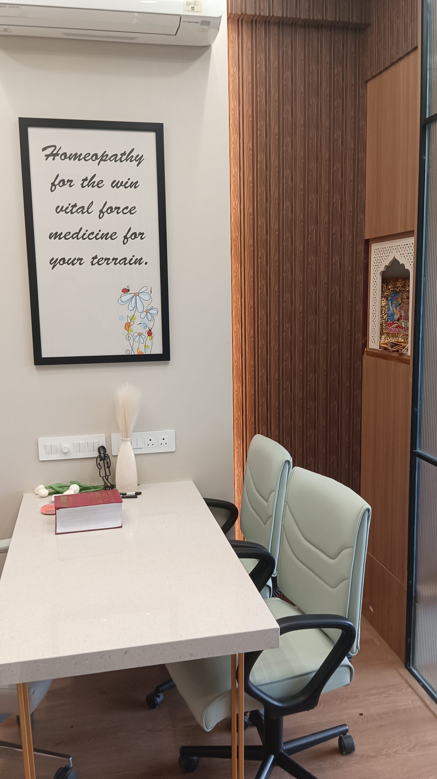Small meeting space featuring a round white table, wooden accent wall with built-in shelves, modern chairs, and warm ambient lighting.