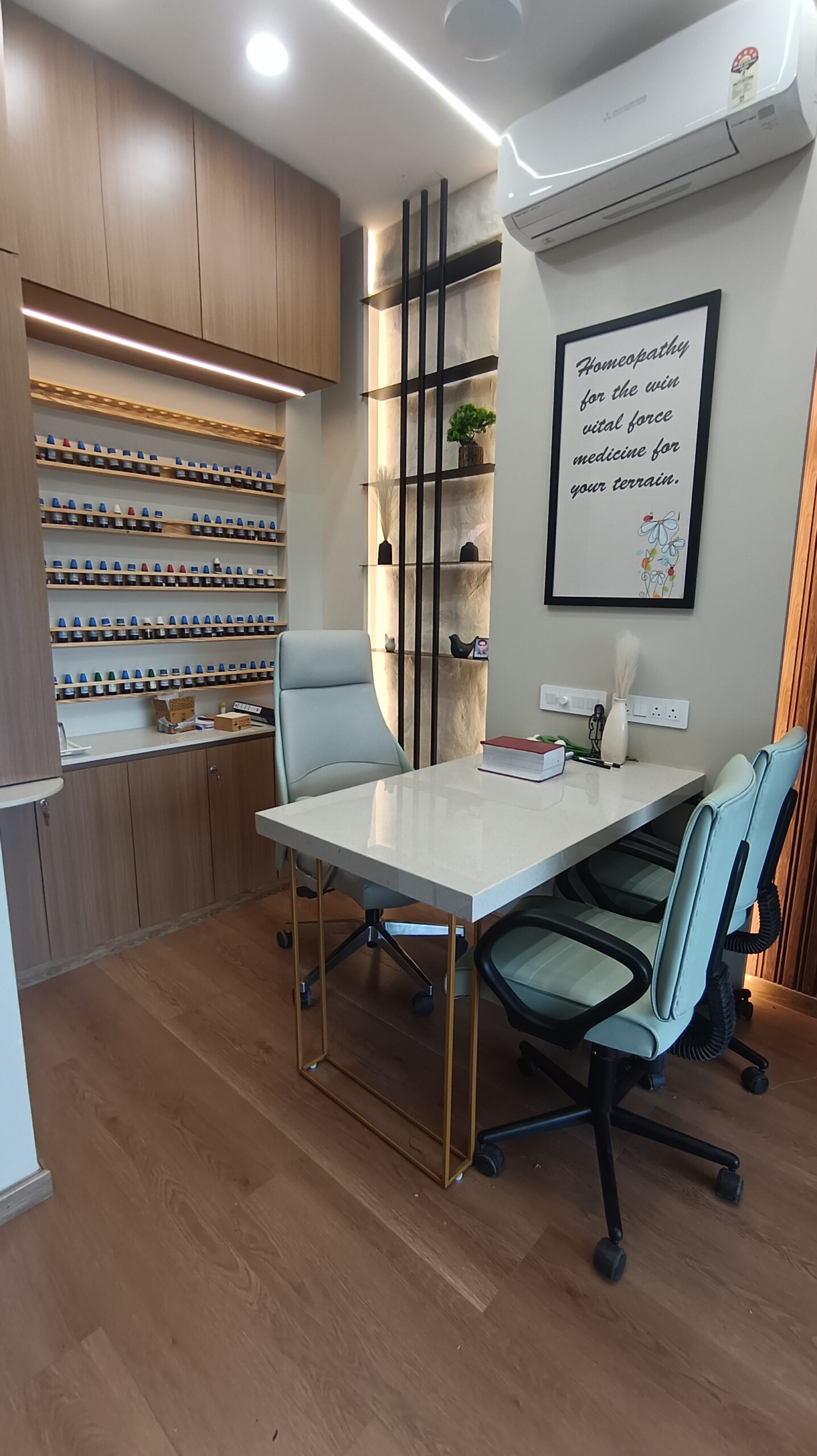 Small office lounge nook featuring a modern lounge chair, round side table, soft lighting, and textured wall panel accents in muted colors.
