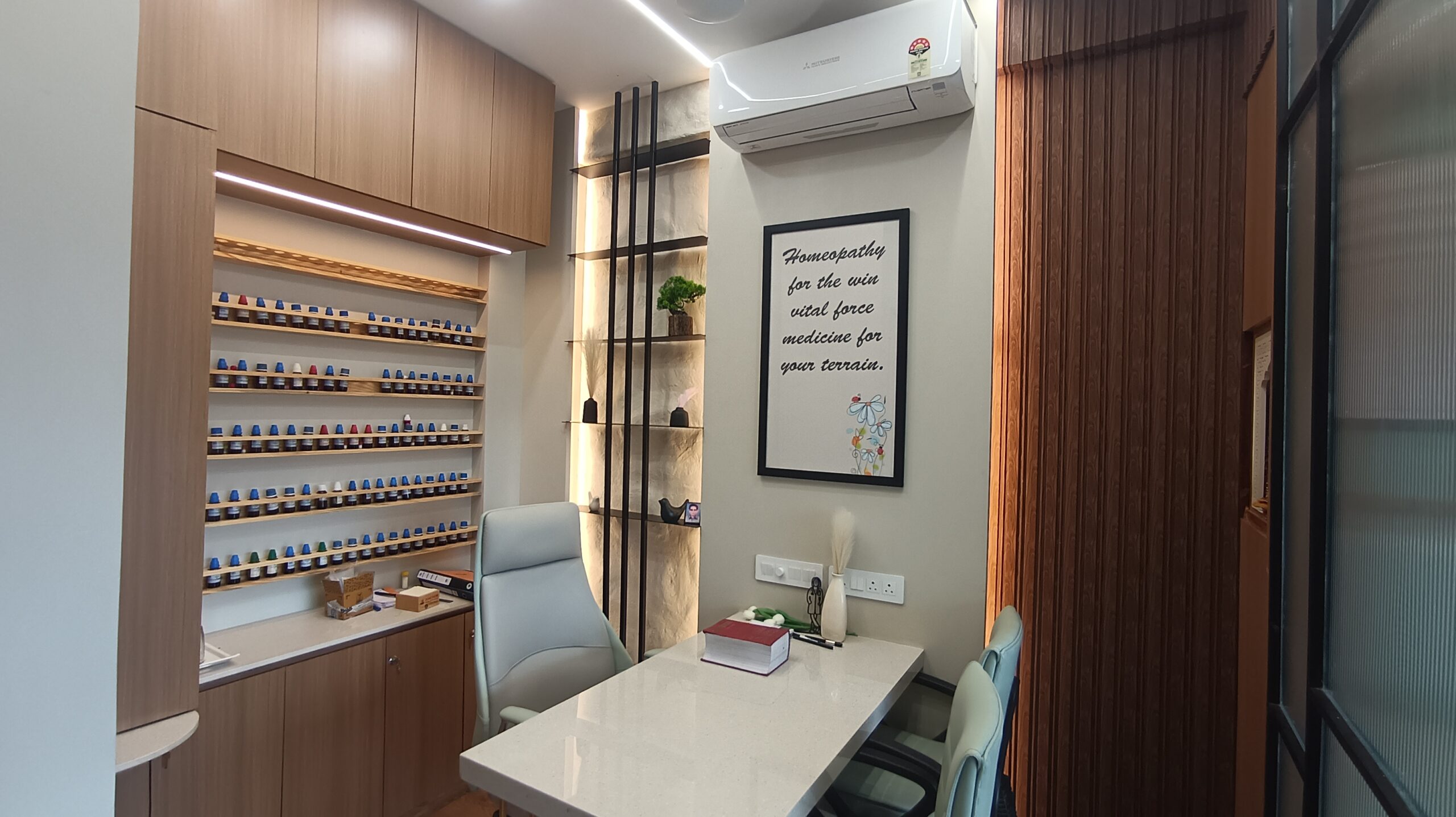 Small breakout area in an office setting featuring a cushioned lounge chair, round table, wood-paneled walls, and soft, neutral color tones.